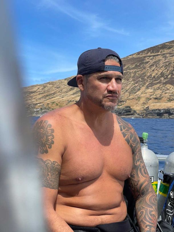 Scuba diver on the boat with the wetsuit half mast