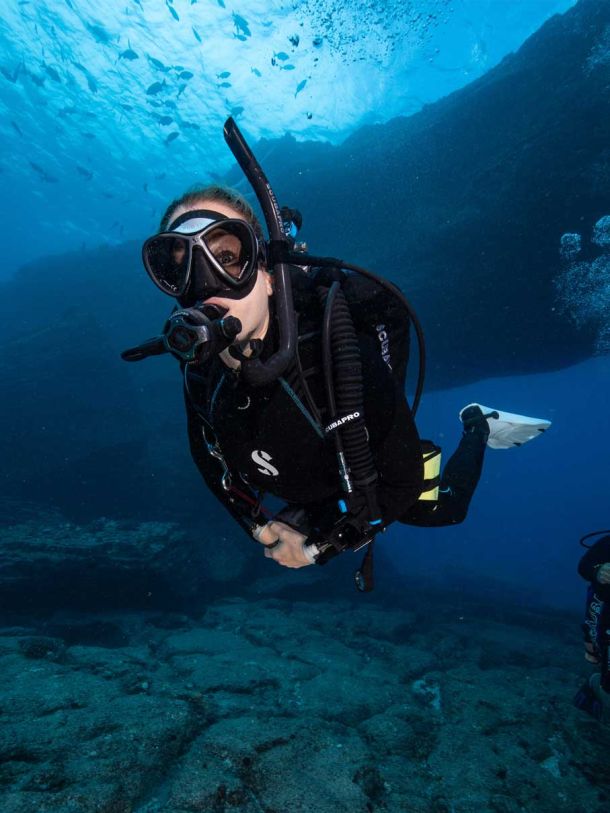 Scuba diver going through a small caver in Kauai