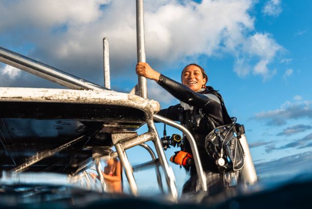 Beginner scuba diver happy after her first dive in Kauai climbing up the lather on the Seasport Divers boat