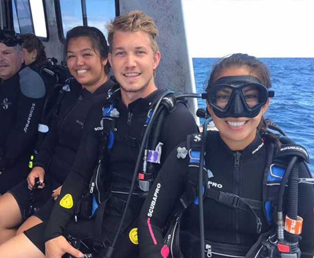Happy scuba divers sitting on a boat ready to scuba dive Kauai