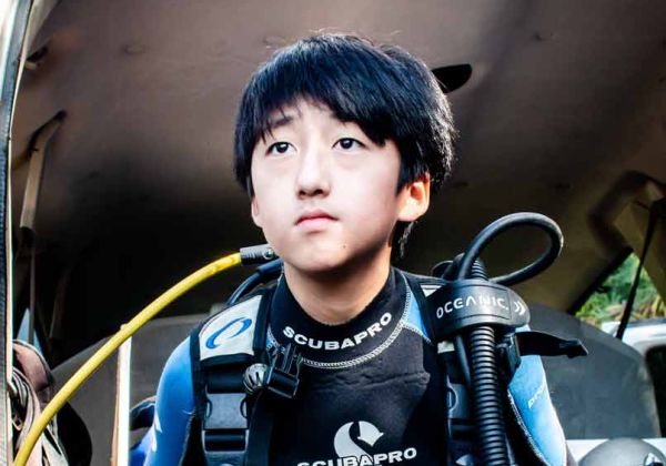 Kid wearing scuba diving equipment and ready to go scuba diving