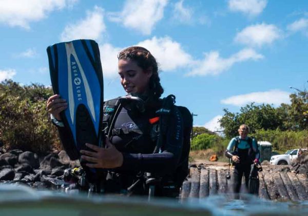 Young girl in the water donning her scuba diving fins before diving Koloa Landing