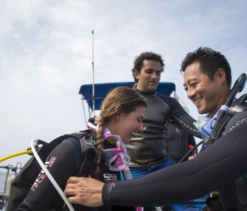 Three scuba divers getting their scuba equipment ready while on the boat