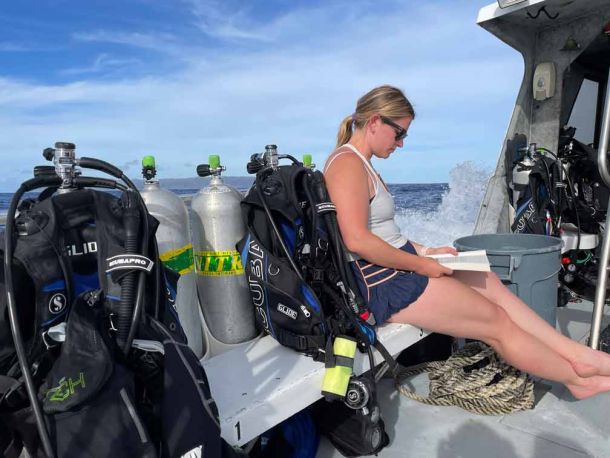Guest relaxing reading a book on the boat ride to scuba dive Niihau