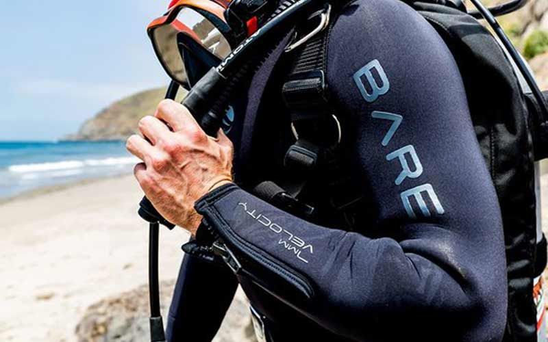Diver wearing a Bare wetsuit and his diving gear at the beach in Kauai